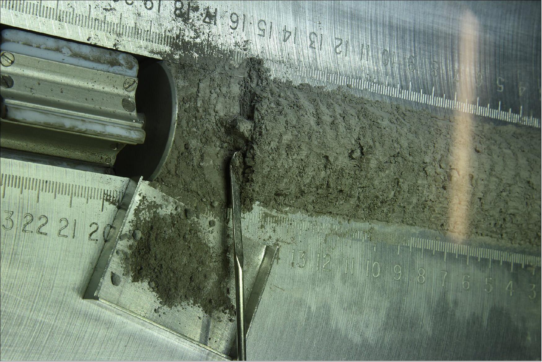 Figure 4: Moon sample 73002 dissection. Sample 73002, the upper section of a double drive tube core sample extracted from the Apollo 17 landing site (paired with lower section 73001 which still remains sealed in a special vacuum container called a CSVC). The core samples material comes from a lunar landslide event in the Taurus Littrow Valley landing site of Apollo 17. Looking down on the top of the core as it is being extracted in 5 mm intervals along its length. In this image the original location and orientation of a larger rock class is observed (image credit: ESA–Francesca McDonald)