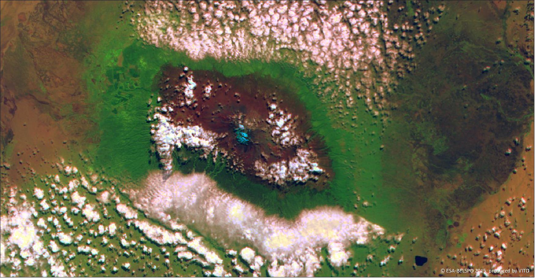 Figure 48: This 100 m resolution false-color image from PROBA-V's main Vegetation camera, acquired on 14 June 2015, shows Kilimanjaro enveloped by clouds to the south and north. The gradual decrease of vegetation with altitude can be seen by the colors changing from green to brown and finally light blue, representing the summit's glacier (image credit: ESA, BelSPO, VITO)