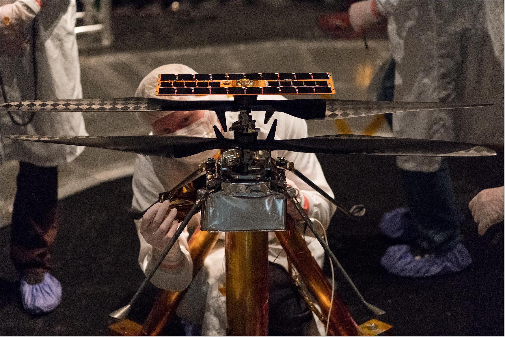 Figure 13: Members of the NASA Mars Helicopter team attach a thermal film to the exterior of the flight model of the Mars Helicopter. The image was taken on Feb. 1, 2019 inside the Space Simulator, a 7.62-meter-wide vacuum chamber at NASA's Jet Propulsion Laboratory in Pasadena, California (image credit: NASA/JPL-Caltech)