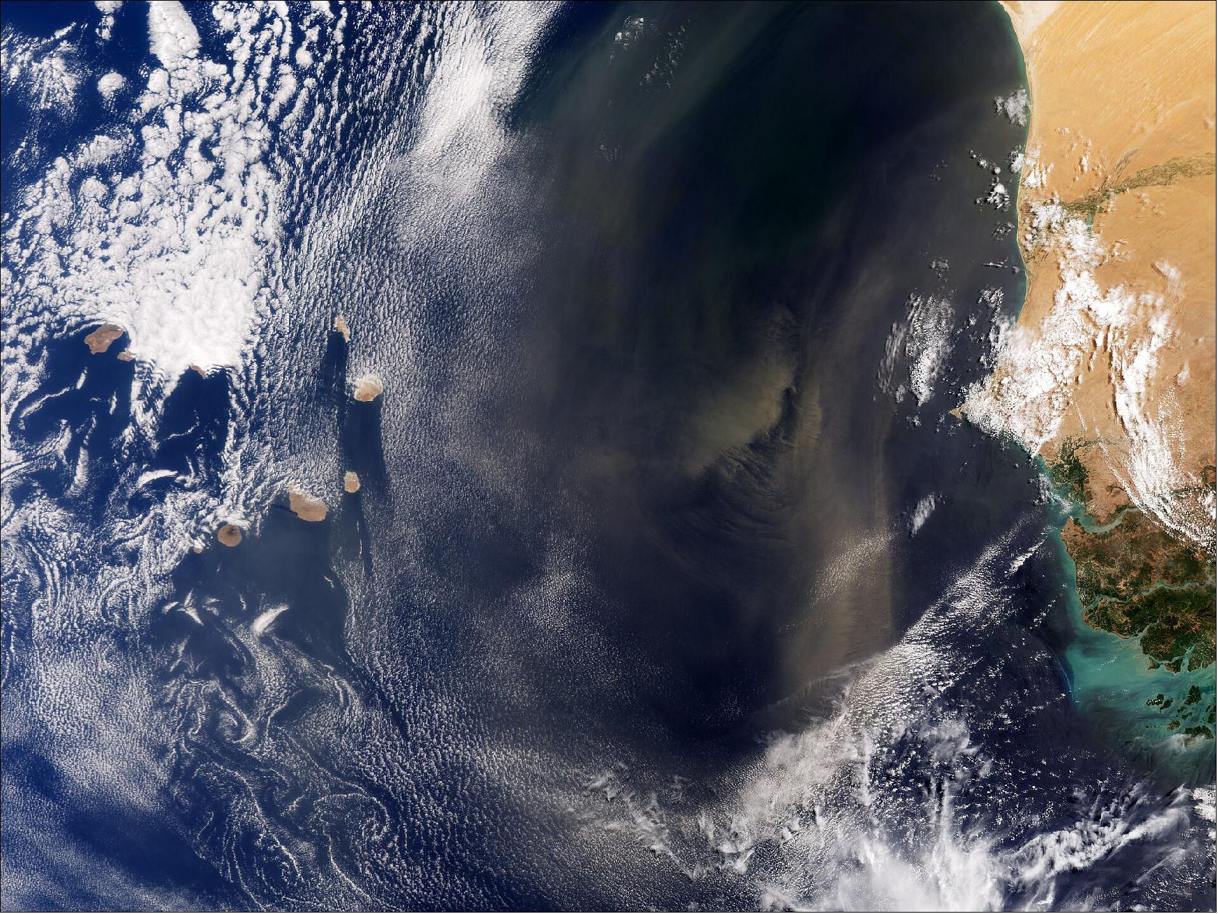 Figure 15: Desert dust blows from Africa. Captured by the Copernicus Sentinel-3 mission on 24 June 2021, this image shows desert dust blowing from the continent of Africa out across the Atlantic Ocean. Several of the small islands that make up the archipelago of Cabo Verde can be seen peeking out from beneath the clouds. These volcanic islands lie in the Atlantic Ocean about 570 km off the west coast of Senegal and Mauritania, which frame the image on the right. The sand comes mainly from the Sahara and Sahel region. Owing to Cabo Verde's position and the trade winds, these storms are not uncommon. - During September 2021, Cabo Verde is the site of an extensive field campaign to validate data from ESA's Aeolus wind mission (image credit: ESA, the image contains modified Copernicus Sentinel-3 data (2021), processed by ESA, CC BY-SA 3.0 IGO)