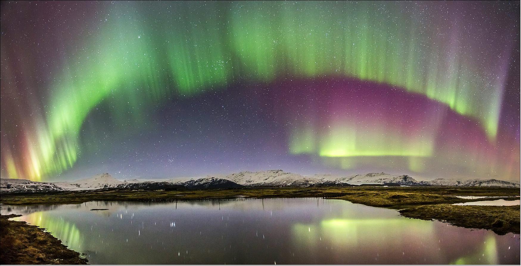 Figure 14: Aurora over Icelandic lake. This dramatic panorama shows a colorful, shimmering auroral curtain reflected in a placid Icelandic lake. The image was taken on 18 March 2015 by Carlos Gauna, near Jökulsárlón Glacier Lagoon in southern Iceland. The celestial display was generated by a coronal mass ejection, or CME, on 15 March. Sweeping across the inner Solar System at some 3 million km per hour, the eruption reached Earth, 150 million kilometers away, in only two days. The gaseous cloud collided with Earth's magnetic field at around 04:30 GMT on 17 March. - When the charged particles from the Sun penetrate Earth's magnetic shield, they are channelled downwards along the magnetic field lines until they strike atoms of gas high in the atmosphere. Like a giant fluorescent neon lamp, the interaction with excited oxygen atoms generates a green or, more rarely, red glow in the night sky, while excited nitrogen atoms yield blue and purple colors (photo credit: C. Gauna)