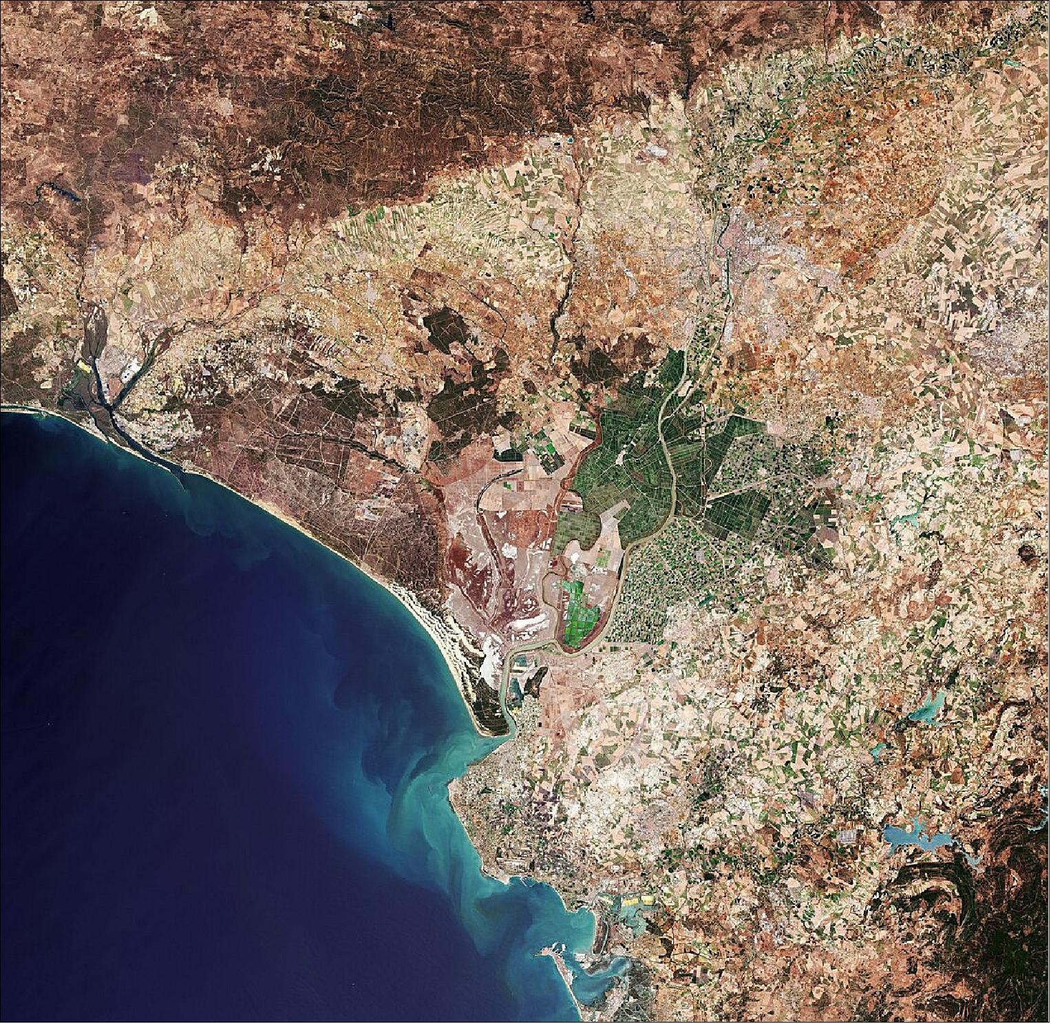 Figure 10: Seville, visible towards the top right of this image, is the capital of Andalusia and the fourth largest city in Spain. An inland port, it lies on the Guadalquivir River and while the original course of the river is visible snaking through the city on the right, we can see where water has also been redirected into a straighter course on the left. At over 650 km long, the Guadalquivir is one of the longest rivers in Spain, extending way beyond the frame of this image. Nevertheless, it can be seen winding its course all the way from the top right of the image, just south of the Sierra Norte mountain range, to the Gulf of Cádiz where it empties into the Atlantic Ocean. On route, this major river serves as a source for irrigation – here noticeable in the top right of the image, but mainly to the south of Seville where large green agricultural fields appear in sharp contrast to the surrounding drier brown land. This image, captured on 21 June 2019 with Sentinel-2, is also featured on the Earth from Space video program (image credit: ESA, the image contains modified Copernicus Sentinel data (2019), processed by ESA, CC BY-SA 3.0 IGO)