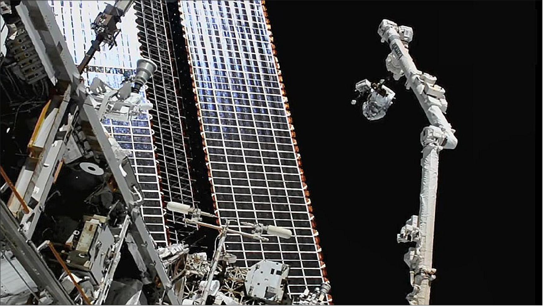 Figure 27: NASA spacewalker Thomas Marshburn (upper right) rides the Canadarm2 robotic arm to the worksite to replace a station antenna system (image credit: NASA TV)