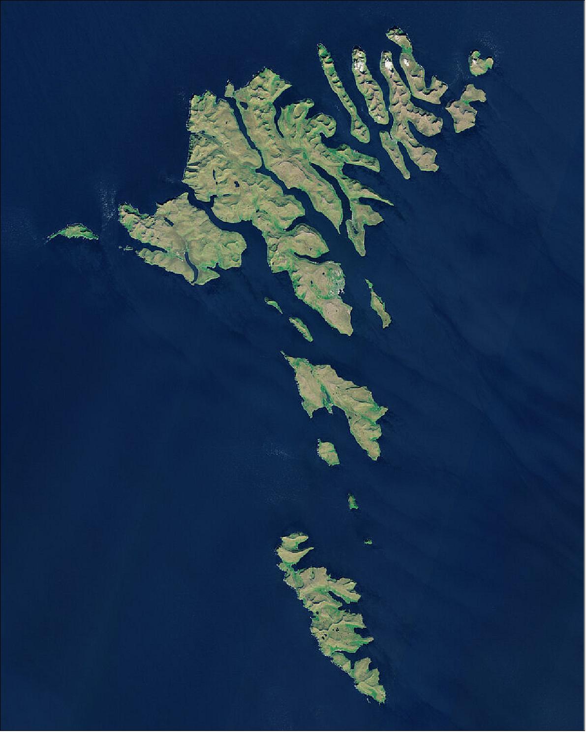 Figure 67: In this image of Sentinel-2, captured on 21 June 2018, several clouds can be seen over the Northern Isles, top right of the image. Low vegetation is visible in bright green. The unique landscape of the Faroe Islands was shaped by volcanic activity approximately 50 to 60 million years ago. The original plateau was later restructured by the glaciers of the ice age and the landscape eroded into an archipelago characterized by steep cliffs, deep valleys and narrow fjords. This image is also featured on the Earth from Space video program (image credit: ESA, the image contains modified Copernicus Sentinel data (2018), processed by ESA, CC BY-SA 3.0 IGO)