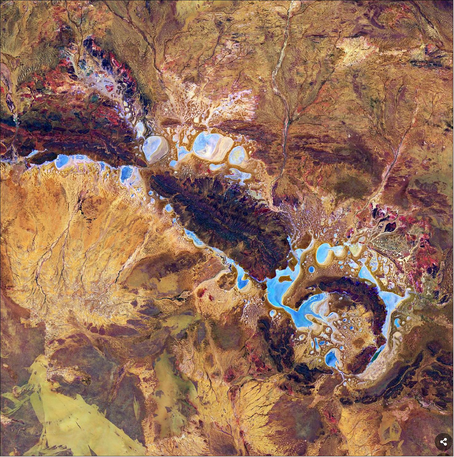 Figure 35: Located around 100 km northeast of the small town Wiluna, the Shoemaker Impact Structure was renamed in honor of Eugene Shoemaker, a planetary geologist and pioneer in impact crater studies. This false-color image was processed by selecting spectral bands that can be used for classifying geological features, allowing us to clearly identify the concentric rings in the image. The light blue areas are saline and ephemeral lakes including Nabberu, Teague, Shoemaker and other smaller ponds (image credit: ESA, the image contains modified Copernicus Sentinel data (2021), processed by ESA, CC BY-SA 3.0 IGO)