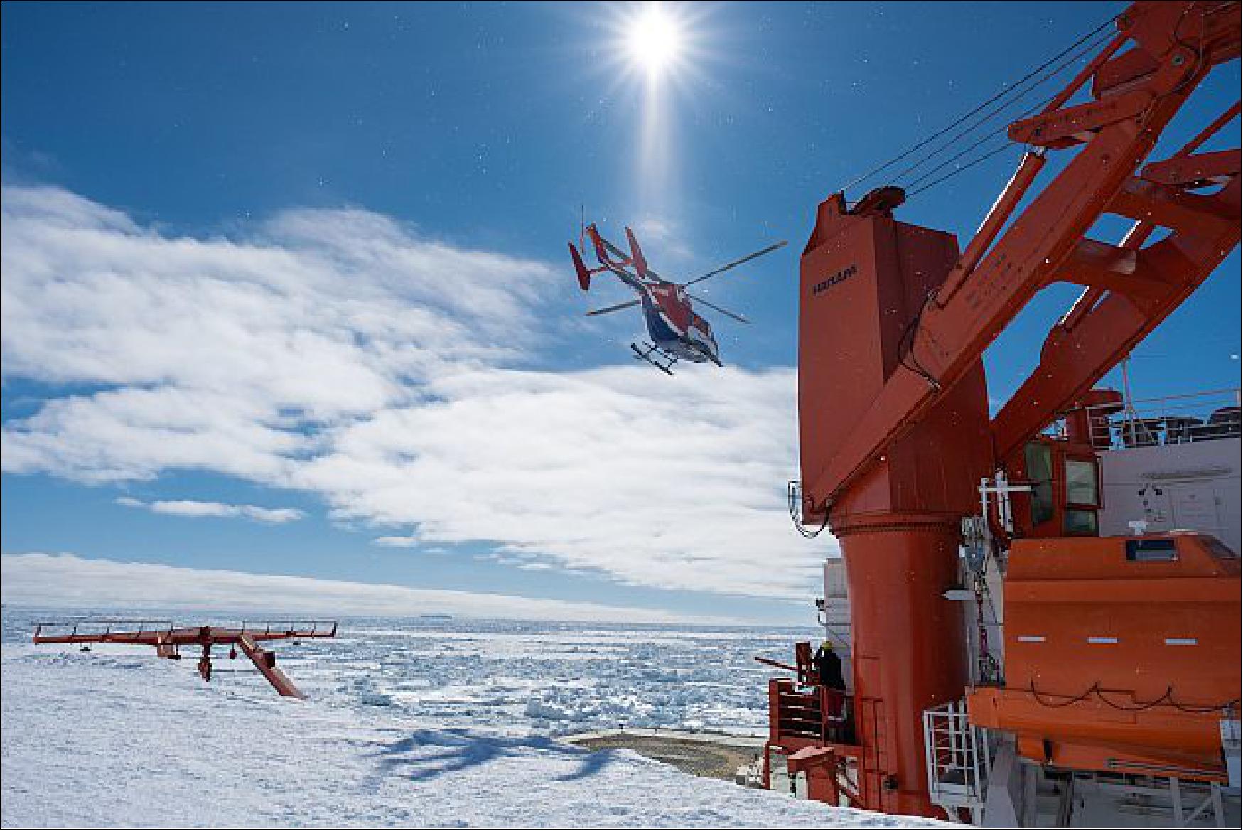 Figure 15: A helicopter taking off from the stern of Polarstern, docked next to the shelf ice (image credit: DLR/NASA/Jess Bunchek)