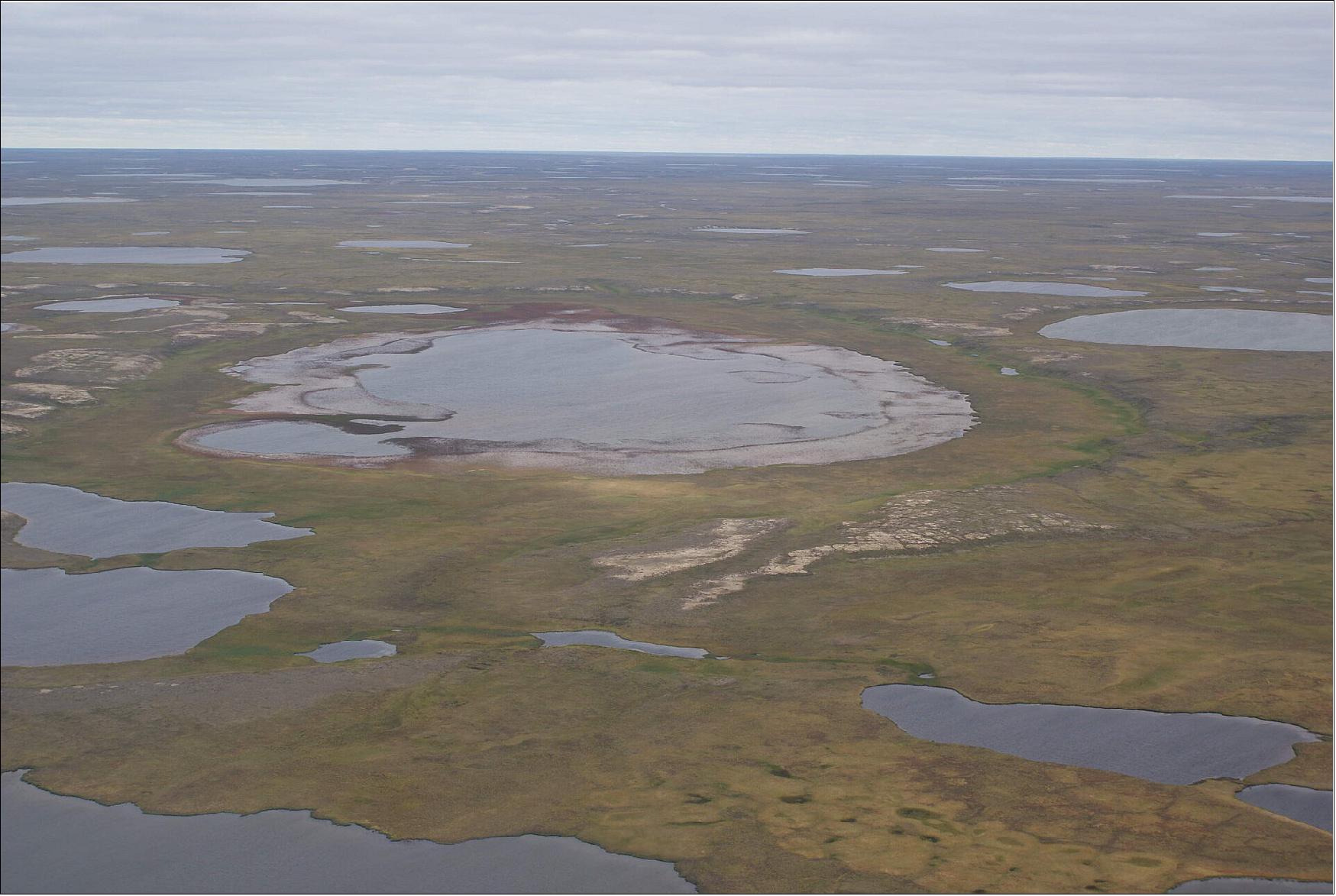 Figure 1: The image shows a partially drained lake on the Yamal Peninsula in northwest Siberia. The rapid thaw of permafrost, as a result of climate change, has huge impacts on the natural environment. Lakes such as this can drain suddenly when the underlying permafrost thaws (image credit: ESA, A. Bartsch)