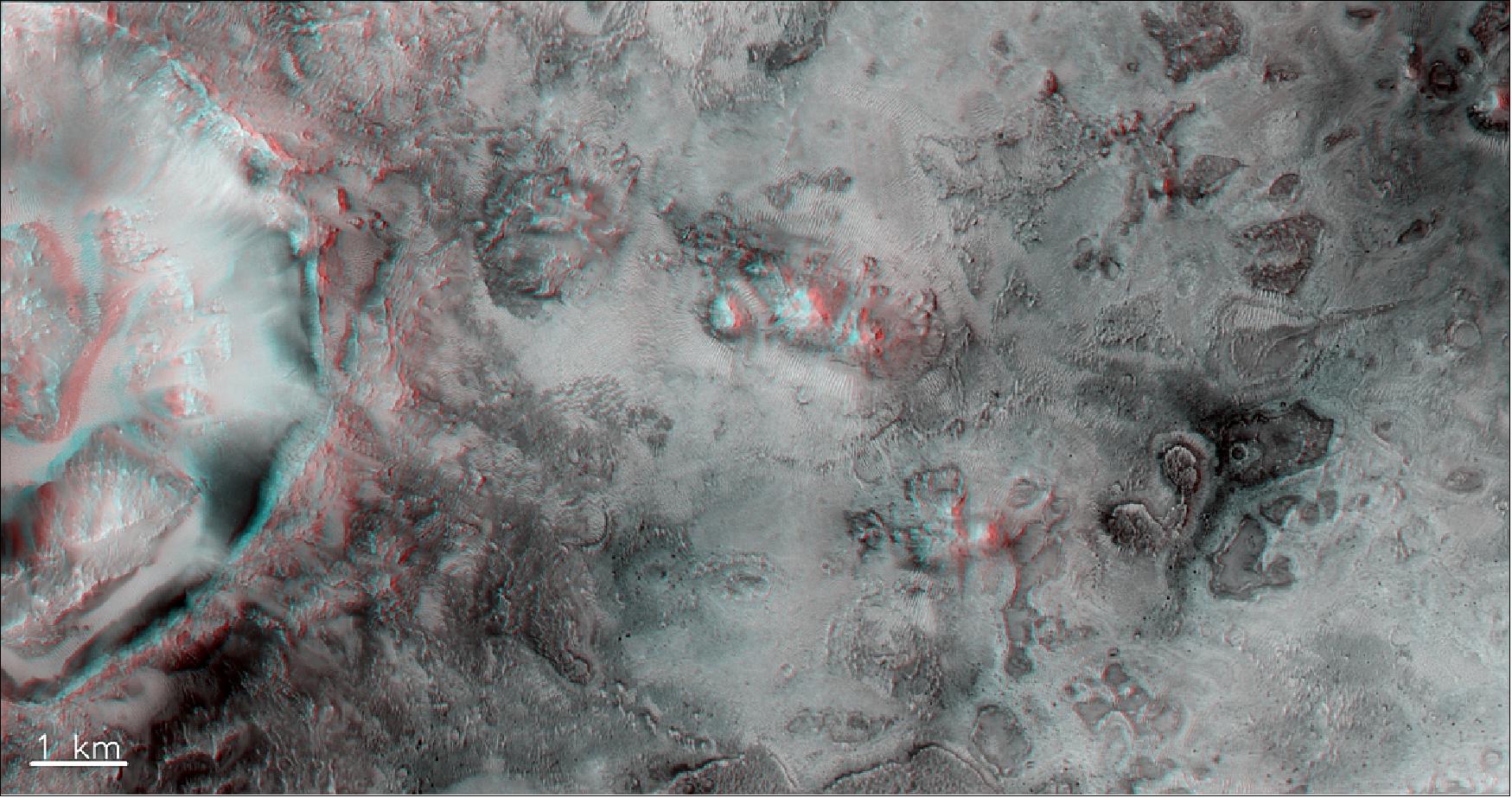 Figure 82: A portion of a crater (left) and rough terrain outside the crater at the boundary between the Syrtis and Isidis regions of Mars, south of the landing site foreseen for NASA’s Mars 2020 rover in Jezero Crater. Use red-blue stereo ‘3D’ glasses to best enjoy this view. It was created from a stereo pair taken by the CaSSIS instrument onboard the ESA-Roscosmos ExoMars TGO on 29 December 2018. The image is centered at 20.73ºN/79.27ºE and measures about 7 km on the short side (image credit: ESA/Roscosmos/CaSSIS, CC BY-SA 3.0 IGO)