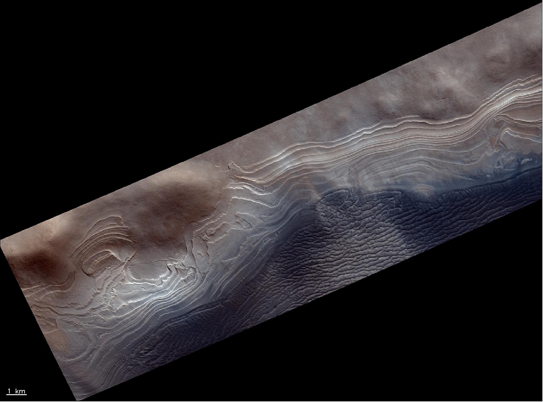 Figure 77: This image shows the edge of a layered mound in the Burroughs crater on Mars. It is located about 200 km to the northwest of the northernmost edge of the planet’s south polar ice cap. The image was taken by the CaSSIS instrument onboard the ESA-Roscosmos ExoMars TGO and captures a strip of the surface measuring about 25 km x 9 km. The image was taken on 16 December 2018 and is centered at 71.8ºS/114.5ºE (image credit: ESA/Roscosmos/CaSSIS, CC BY-SA 3.0 IGO)