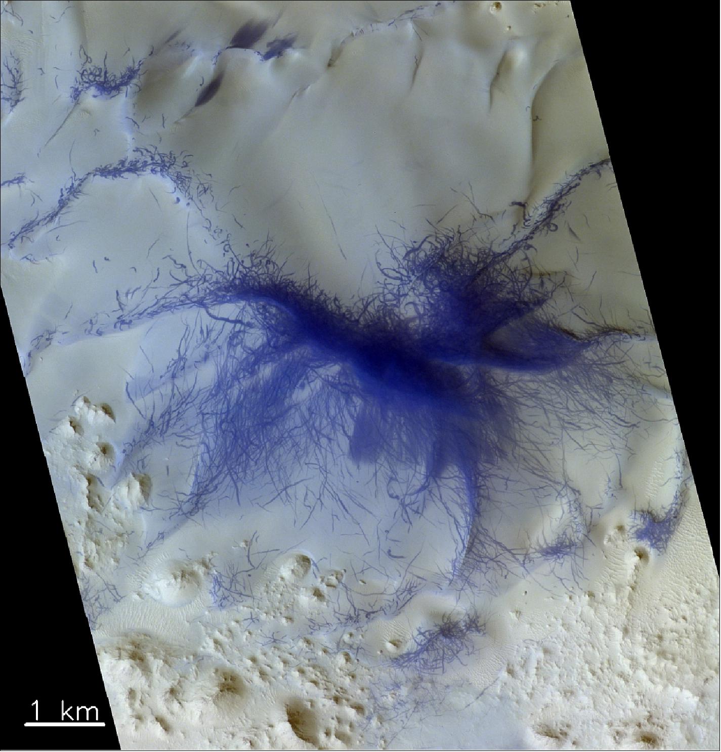 Figure 73: This remarkable image was taken in the Terra Sabaea region of Mars, west of Augakuh Vallis, by the CaSSIS (Color and Stereo Surface Imaging System) onboard the ESA-Roscosmos ExoMars TGO. This mysterious pattern sits on the crest of a ridge, and is thought to be the result of dust devil activity – essentially the convergence of hundreds or maybe even thousands of smaller martian tornadoes. The image was taken on 8 February 2019 and is centered at 26.36ºN/56.96ºE. North is up (image credit: ESA/Roscosmos/CaSSIS, CC BY-SA 3.0 IGO)