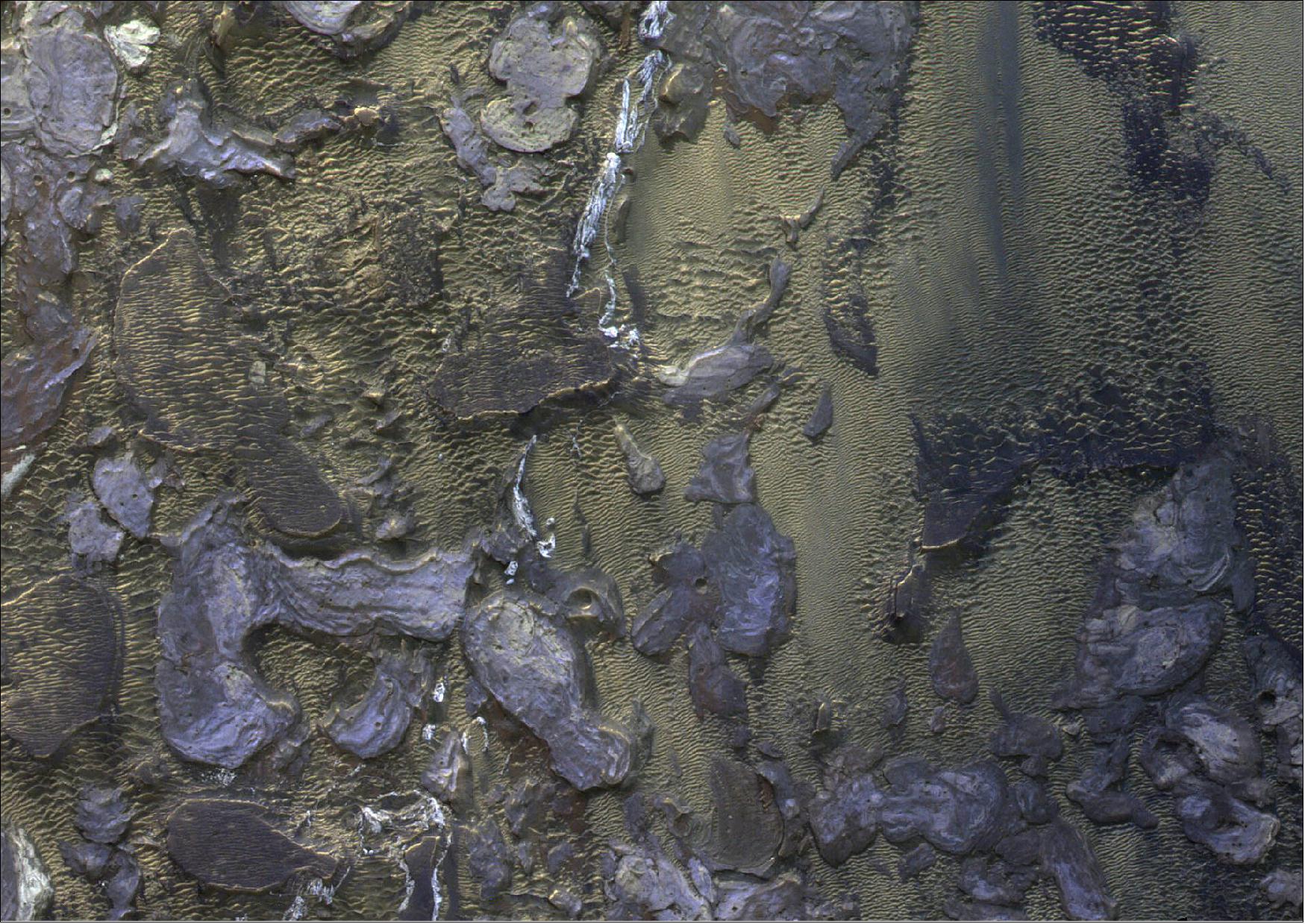 Figure 38: The section seen here is about 5 x 6 km in size. It is a color infrared image (combining the NIR, PAN and BLU filters of CaSSIS), and emphasizes the spectral diversity of landforms and sediments on the surface. It shows details of a blocky deposit on the floor of Melas Chasma that is consistent with an eroded and exposed landslide deposit. Windblown ripples are abundant and interspersed between the blocks. The image was taken on 19 October 2020 and featured on the February 2021 cover of Nature Geoscience (image credit: ESA/Roscosmos/CaSSIS, CC BY-SA 3.0 IGO)