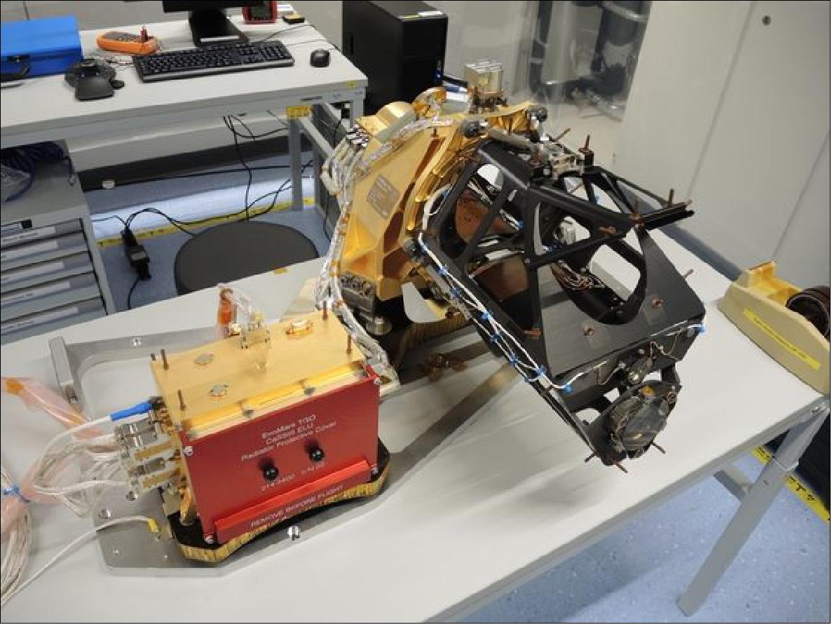 Figure 138: The CaSSIS instrument on a bench in the University of Bern laboratory in Nov. 2015. The electronics unit (left) controls the telescope (right). The black part of the instrument is the telescope structure. The main mirror can be seen in the center. The telescope is cantilevered off the gold colored support structure (image credit: University of Bern)