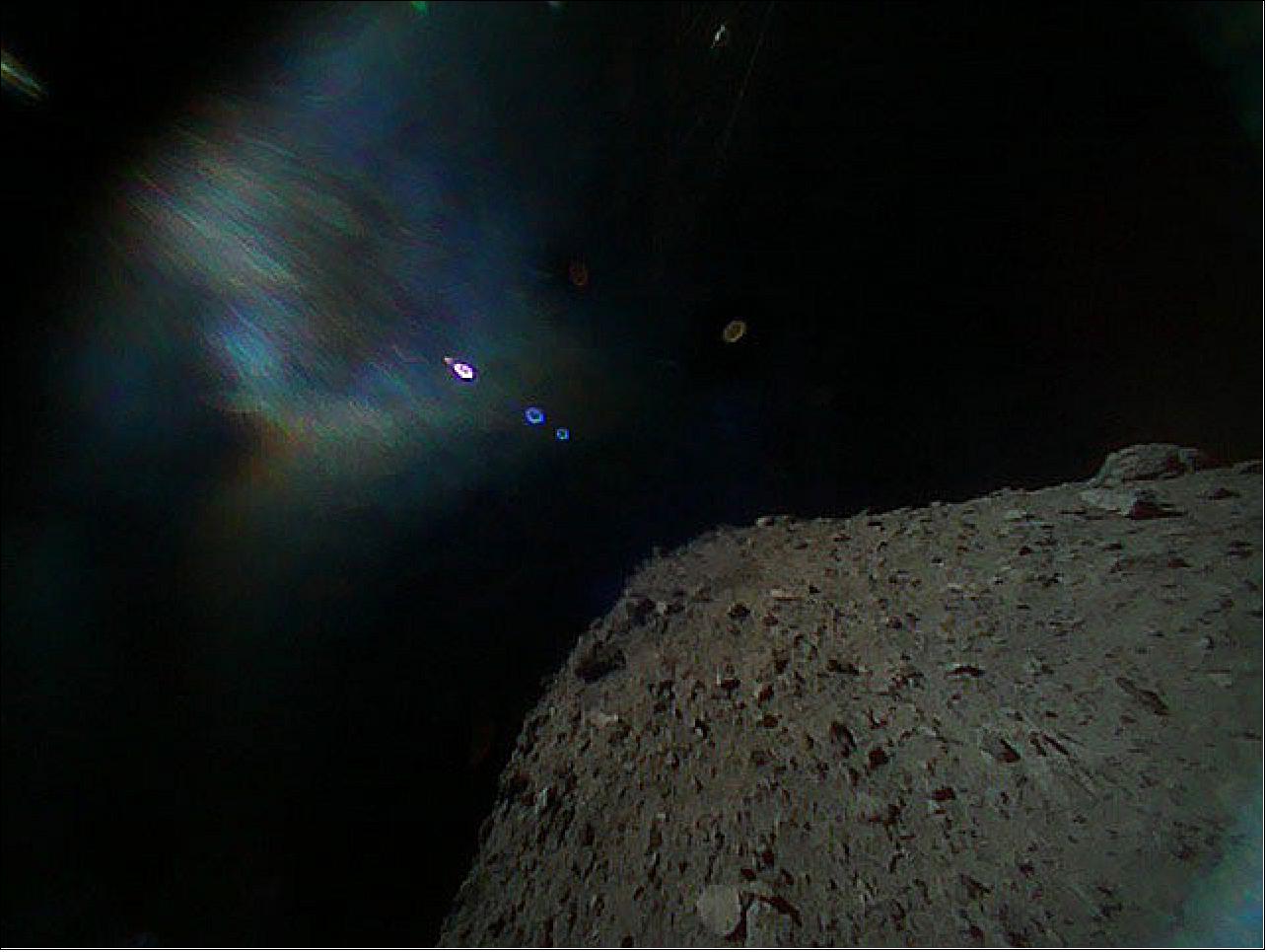 Figure 94: Image captured by Rover-1B on September 21 at around 13:07 JST. This color image was taken immediately after separation from the spacecraft. The surface of Ryugu is in the lower right. The colored blur in the top left is due to the reflection of sunlight when the image was taken (image credit: JAXA)