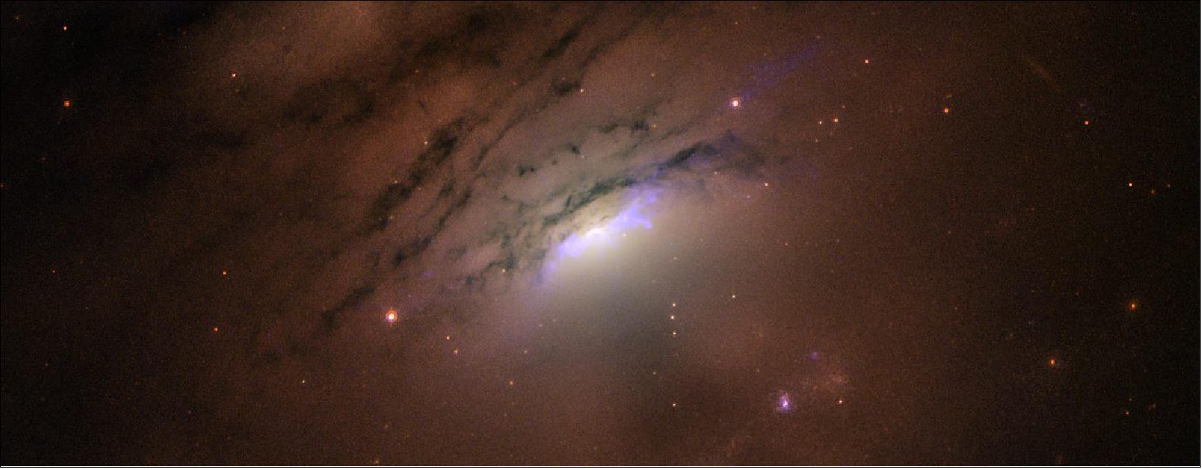 Figure 12: This Hubble Space Telescope image of the heart of nearby active galaxy IC 5063 reveals a mixture of bright rays and dark shadows coming from the blazing core, home of a supermassive black hole. Astronomers suggest that a ring of dusty material surrounding the black hole may be casting its shadow into space. According to their scenario, this interplay of light and shadow may occur when light blasted by the monster black hole strikes the dust ring, which is buried deep inside the core. Light streams through gaps in the ring, creating the brilliant cone-shaped rays. However, denser patches in the disk block some of the light, casting long, dark shadows through the galaxy. - This phenomenon is similar to sunlight piercing our Earthly clouds at sunset, creating a mixture of bright rays and dark shadows formed by beams of light scattered by the atmosphere. However, the bright rays and dark shadows appearing in IC 5063 are happening on a vastly larger scale, shooting across at least 36,000 light-years. IC 5063 resides 156 million light-years from Earth. The observations were taken on March 7 and Nov. 25, 2019 by Hubble's Wide Field Camera 3 and Advanced Camera for Surveys [image credit: NASA, ESA, STScI and W. P. Maksym (CfA)]