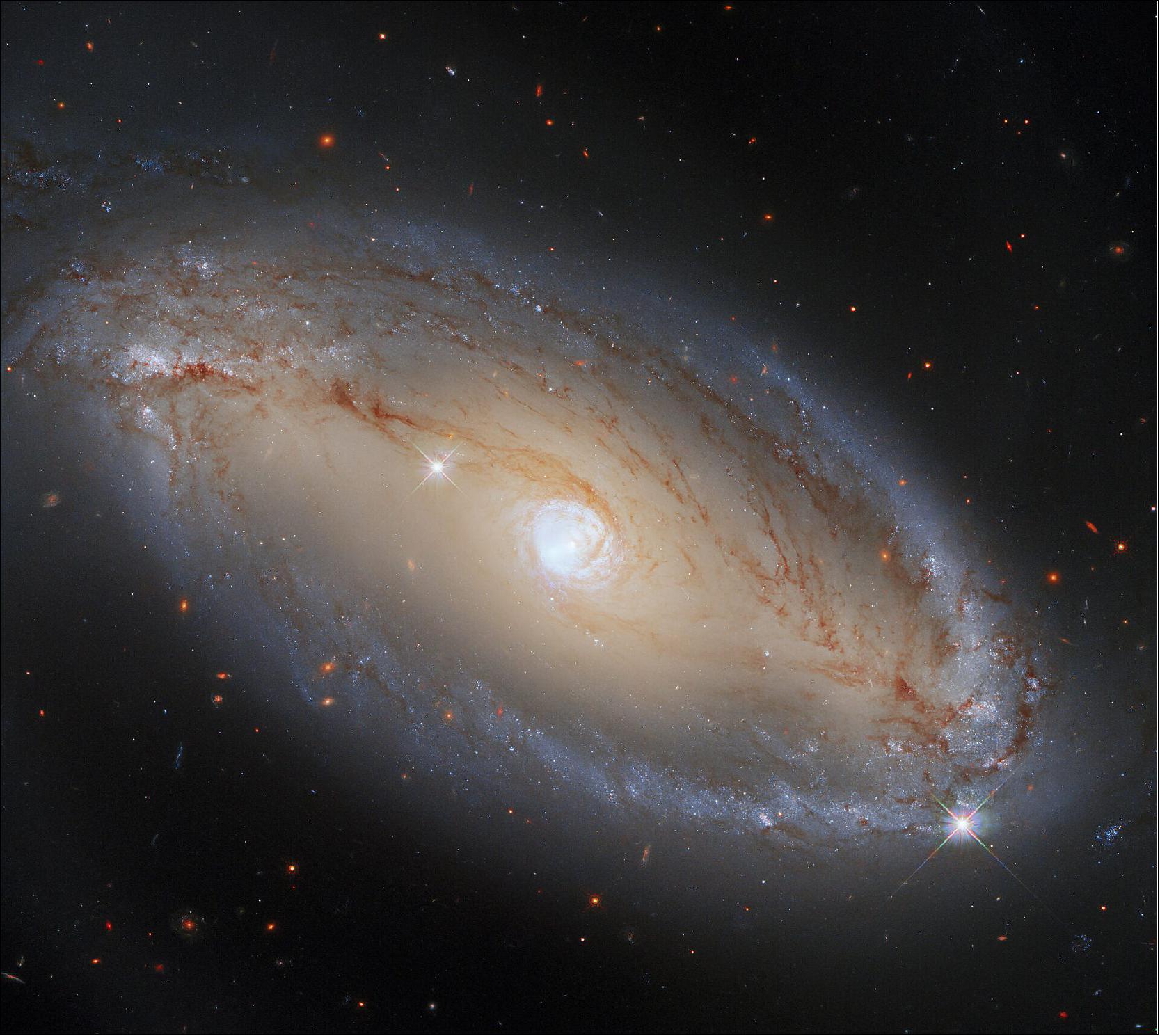 Figure 43: In this image, NGC 5728 appears to be an elegant, luminous, barred spiral galaxy. What this image does not show, however, is that NGC 5728 is also a monumentally energetic type of galaxy, known as a Seyfert galaxy. This extremely energetic class of galaxies are powered by their active cores, which are known as active galactic nuclei (AGNs). There are many different types of AGNs, and only some of them power Seyfert galaxies. NGC 5728, like all Seyfert galaxies, is distinguished from other galaxies with AGNs because the galaxy itself can be seen clearly. Other types of AGNs, such as quasars, emit so much radiation that it is almost impossible to observe the galaxy that houses them. As this image shows, NGC 5728 is clearly observable, and at optical and infrared wavelengths it looks quite normal. It is fascinating to know that the galaxy’s center is emitting vast amounts of light in parts of the electromagnetic spectrum that WFC3 just isn’t sensitive to! Just to complicate things, the AGN at NGC 5728’s core might actually be emitting some visible and infrared light — but it may be blocked by the dust surrounding the galaxy’s core (image credit: ESA/Hubble, A. Riess et al., J. Greene; CC BY 4.0)