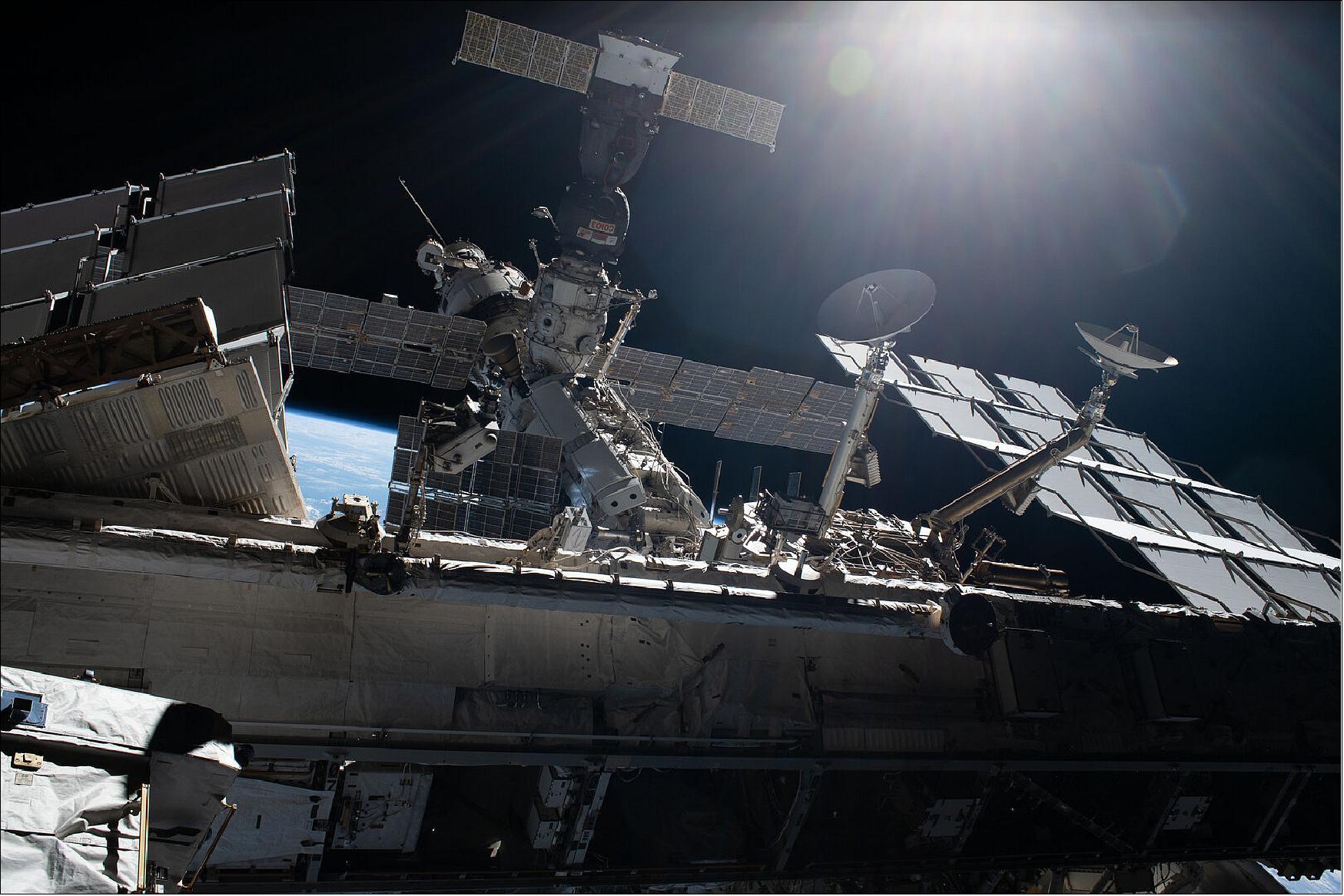 Figure 115: International Space Station with Soyuz. This image taken by ESA astronaut Luca Parmitano from outside the International Space Station on the second spacewalk to service the cosmic ray detecting Alpha Magnetic Spectrometer (AMS-02) on 22 November 2019. The Soyuz MS-13 spacecraft that bought Luca, NASA astronaut Drew Morgan and Roscosmos commander Alexander Skvortsov to space is visible docked to the Zvezda service module of the International Space Station. Due to the AMS worksite being difficult to reach on top of the Station's S3 Truss structure between a pair of solar arrays and radiators, Luca travelled to and from the site on the end of the robotic arm operated by NASA astronaut Jessica Meir from inside the Station (image credit: ESA–Luca Parmitano, CC BY-SA 3.0 IGO)