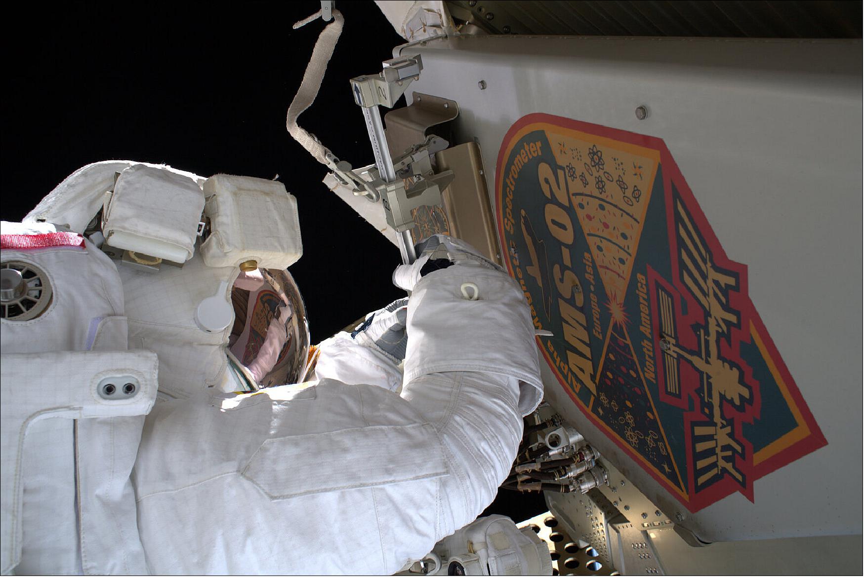 Figure 8: In this image Luca is seen performing his first AMS task, which is to remove the instrument's debris shield and hand it to Drew who will cast it away to burn up harmlessly in Earth's atmosphere. Doing so will provide the pair with their first look at the worksite (image credit: ESA/NASA)