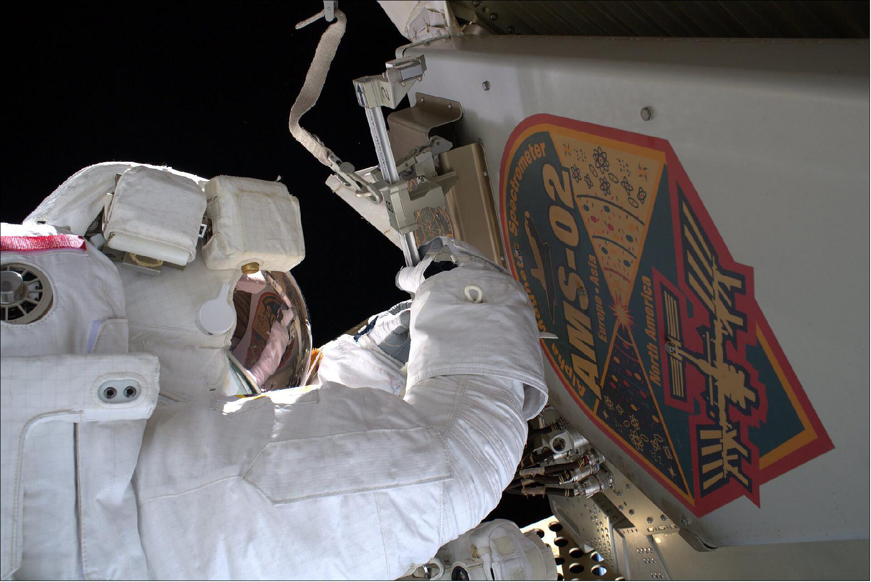 Figure 4: In this image, ESA astronaut Luca Parmitano is seen conducting the first task in a series of four complex spacewalks carried out to maintain AMS-02’s cooling system during his Beyond mission. After removing this debris shield, Luca handed it to NASA astronaut and fellow spacewalker Andrew Morgan who cast it away to burn up harmlessly in Earth’s atmosphere. The pair, and teams on the ground, then got their first look at the worksite. Over 20 new tools were designed for the spacewalks carried out by Luca and Andrew. Though the instrument was never designed to be maintained in orbit, their work extended its lifetime to match that of the Station and will ensure it continues to collect cosmic data to shed light on the origin of our Universe for many years to come (image credit: ESA/NASA)