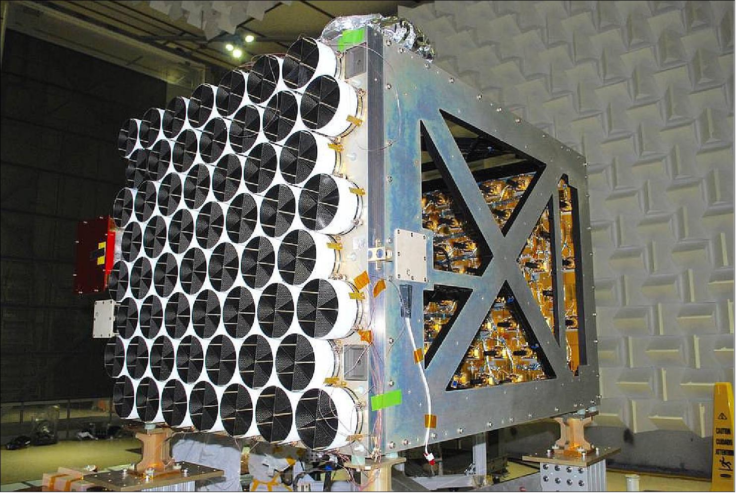 Figure 8: A view of the NICER XTI (X-ray Timing Instrument) without its protective blanketing shows a collection of 56 close-packed sunshades-the white and black cylinders in the foreground-that protect the X-ray optics (not visible here), as well as some of the 56 X-ray detector enclosures, on the gold-colored plate, onto which X-rays from the sky are focused (image credit: NASA, Keith Gendreau)