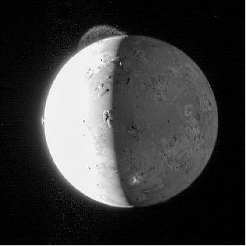 Figure 14: This dramatic image of Io was taken by the Long Range Reconnaissance Imager (LORRI) on New Horizons at 11:04 Universal Time on February 28, 2007, just about 5 hours after the spacecraft's closest approach to Jupiter. This processed image provides the best view yet of the enormous 290-km (180-mile) high plume from the volcano Tvashtar, in the 11 o'clock direction near Io's north pole. The image also shows the much smaller symmetrical fountain of the plume, about 60 km (or 40 miles) high, from the Prometheus volcano in the 9 o'clock direction. The top of a third volcanic plume, from the volcano Masubi, erupts high enough to catch the setting Sun on the night side near the bottom of the image, appearing as an irregular bright patch against Io's Jupiter-lit surface. Several Everest-sized mountains are highlighted by the setting Sun along the terminator, the line between day and night (image credits: NASA/JHUAPL/SwRI)