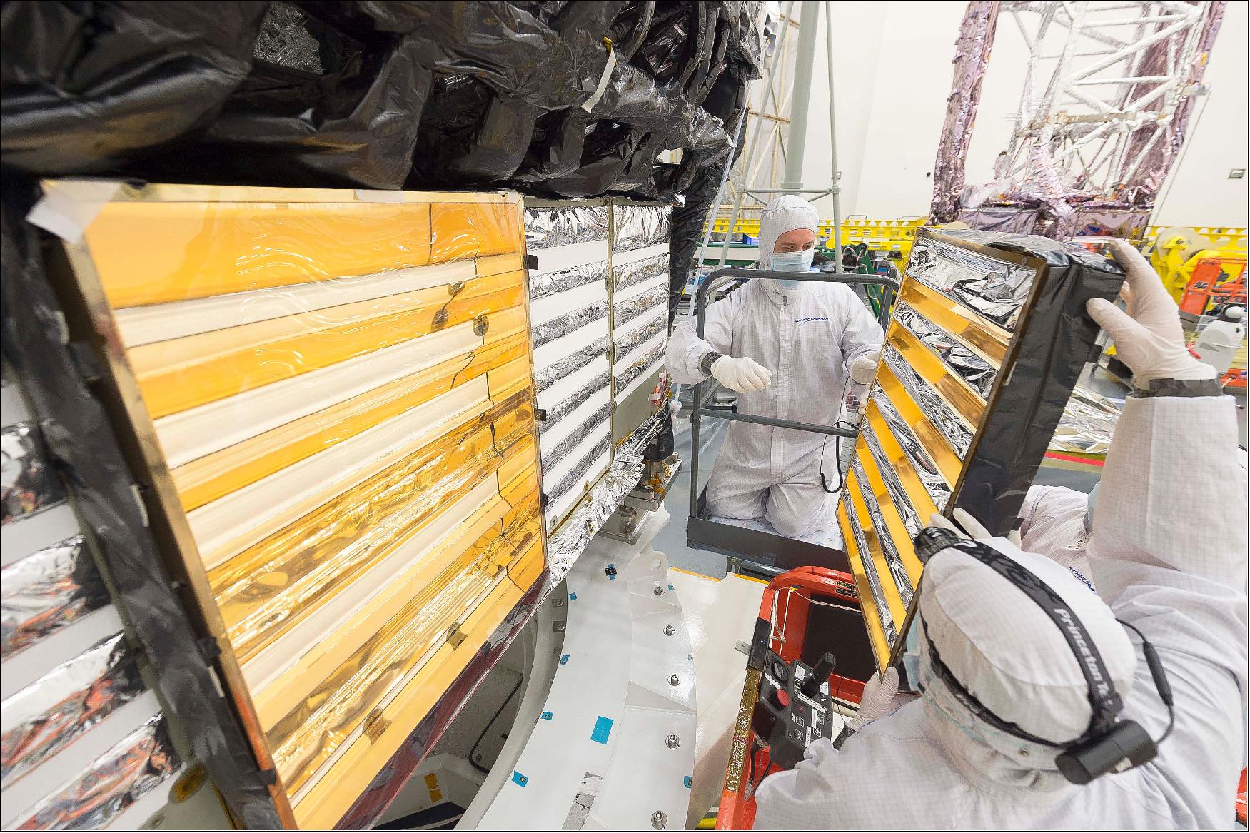 Figure 45: Engineers carefully hold onto a gold-plated baffle as they use a scissor lift to access the back of the integrated science instrument module (ISIM) of NASA's James Webb Space Telescope. They are in the process of reinstalling the baffles, which direct the heat generated by the instrument electronics safely into space and away from any cold areas of the infrared telescope (image credit: NASA/Chris Gunn)