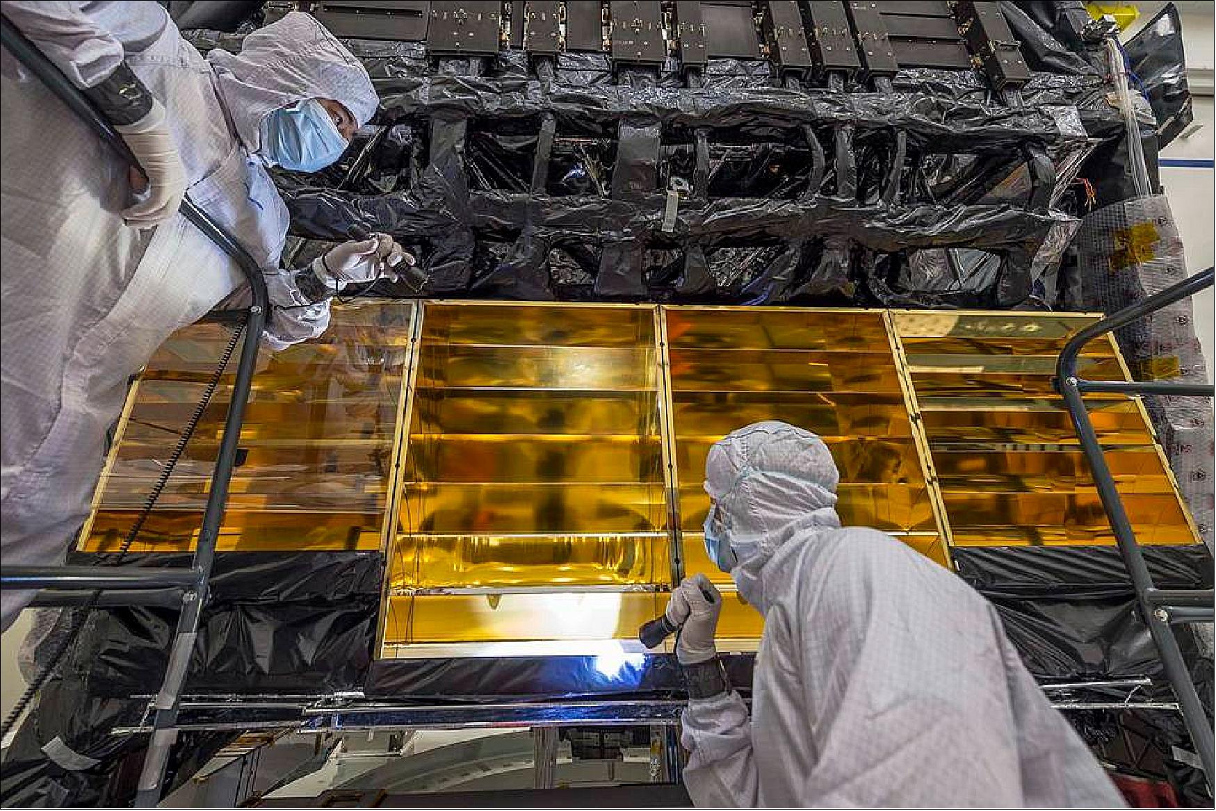 Figure 44: Engineers reinstall one of the gold-plated baffles that helps direct heat away from the integrated science instrument module (ISIM) of NASA's James Webb Space Telescope. The baffles direct the heat generated by the instrument electronics safely into space and away from any cold areas of the infrared telescope image credit: NASA/Chris Gunn)