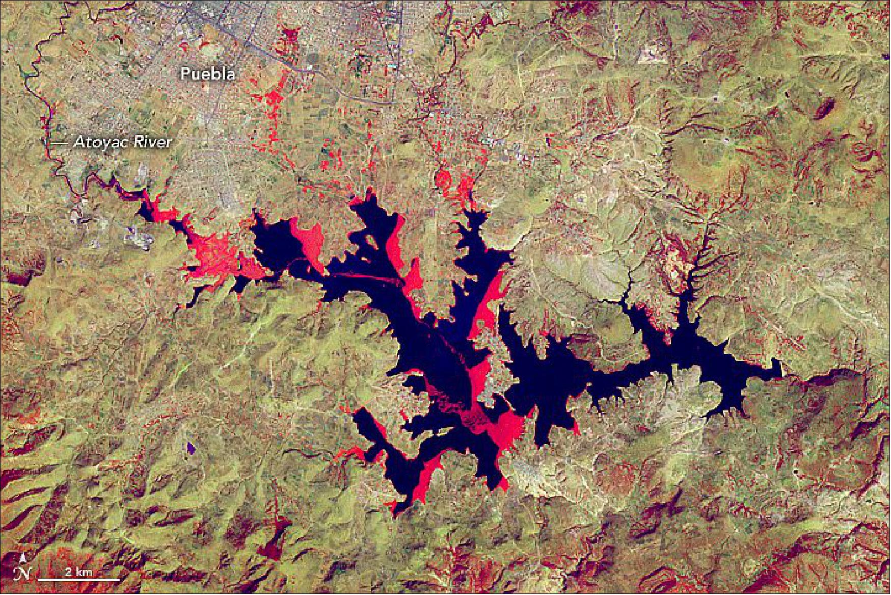 Figure 41: The false-color images show the spread of water hyacinths across Mexico’s Valsequillo reservoir from January 10, 2000 (Figures 41), to January 9, 2020 (Figure 42). The images combine infrared, red, and green wavelengths to help differentiate between water and land. Clear water is blue and vegetation is red (the brighter the red, the more robust the vegetation). The images were acquired by the Enhanced Thematic Mapper Plus on Landsat-7 (bands 4-7-1) and the Operational Land Imager (OLI) on Landsat-8 (bands 5-7-1), respectively (image credit: NASA Earth Observatory, images by Lauren Dauphin, using Landsat data from the U.S. Geological Survey and using data from Kleinschroth, Fritz, et al. (2020). Story by Kasha Patel)