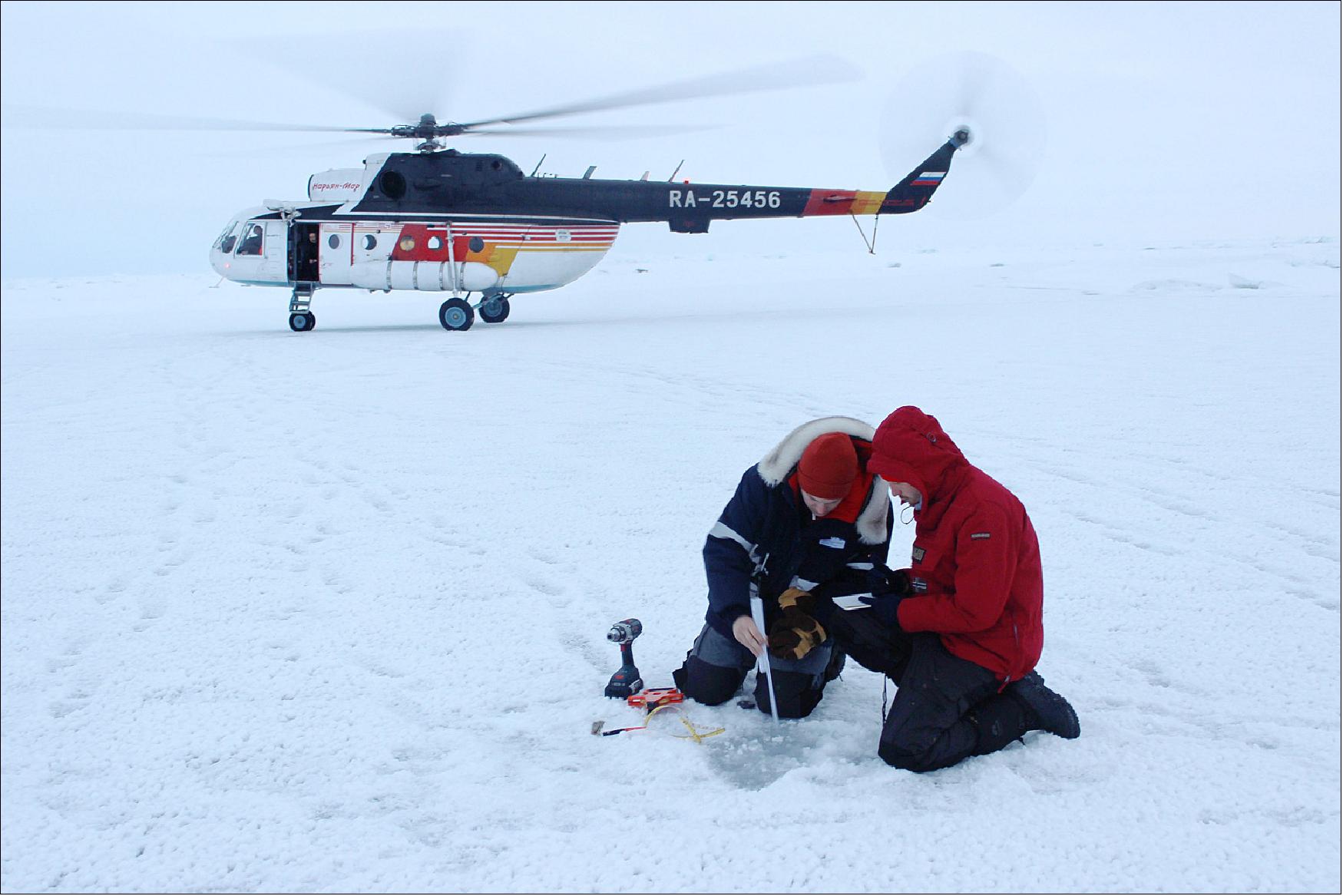 Figure 51: Jan Rohde and Jakob Belter take ice thickness measurements in front of an Mi-8 helicopter in the Central Arctic Ocean (image credit: Daisy Dunne for Carbon Brief)