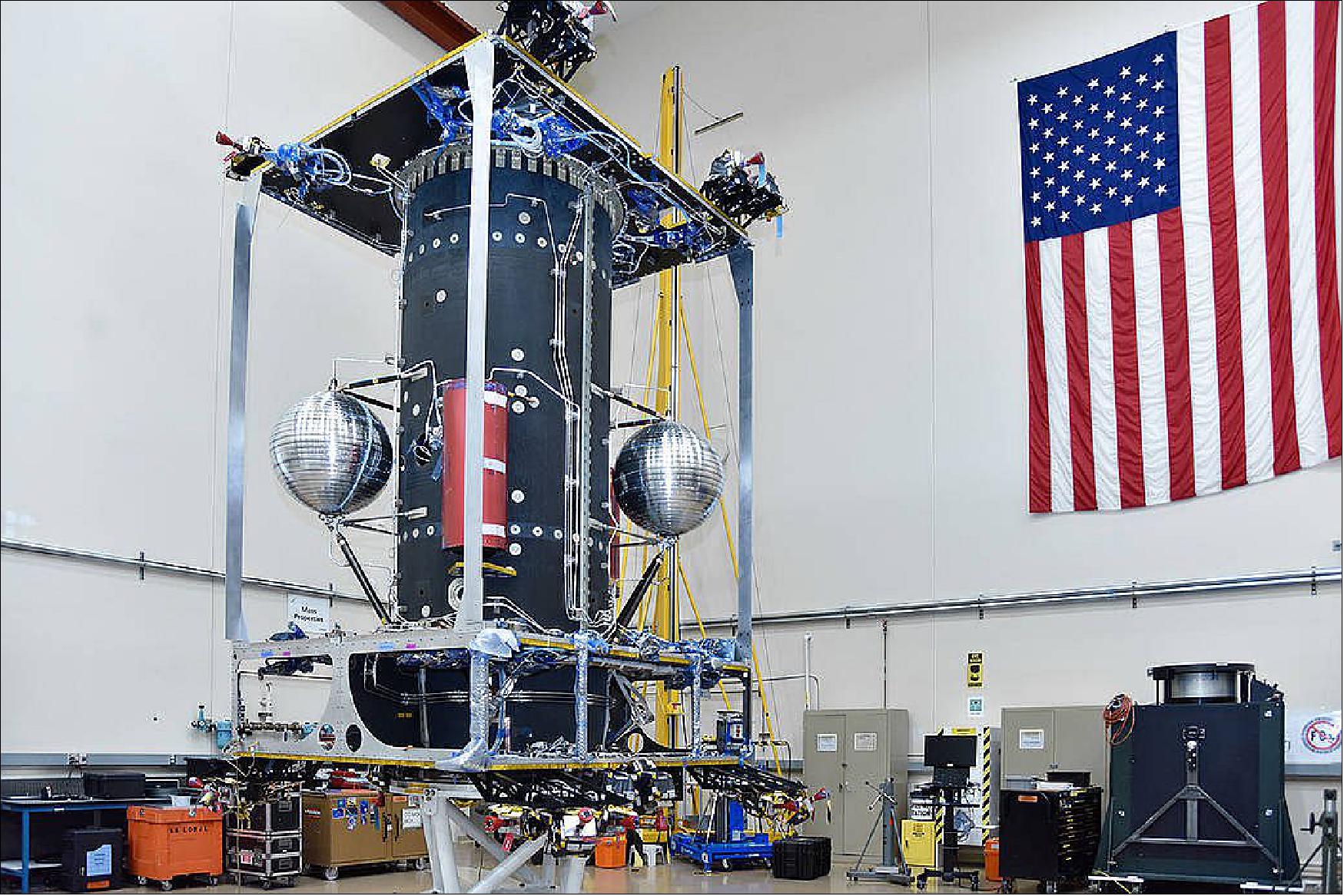 Figure 10: This image, taken by Maxar in their Palo Alto, California, facility, features the OSAM-1 spacecraft bus under development. The 14-foot-tall bus will provide OSAM-1 with power and the ability to maneuver in orbit. To make these maneuvers possible, inside the main cylinder are two large bi-propellant tanks, and the upper and lower deck of the spacecraft feature thrusters. The two silver spheres are filled with mono-propellant fuel that will be used to provide OSAM-1's target client satellite, Landsat 7, with more fuel to demonstrate that robotically refueling a satellite is possible (image credit: Maxar Technologies)