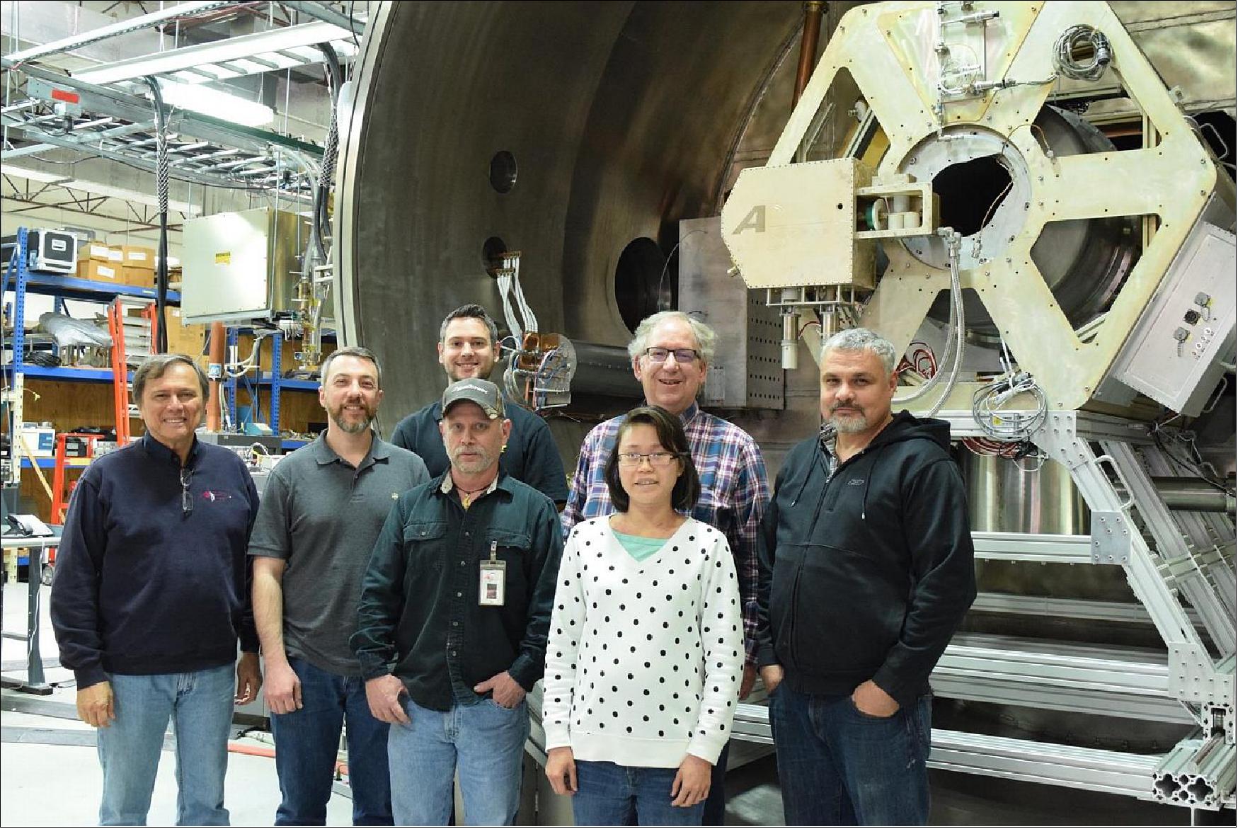 Figure 6: Some of the Ad Astra team members who supported the RF-PPU testing pose in front of the open vacuum chamber at the company's Texas facility. The RF-PPU and part of the test hardware can be seen in background (upper center). The main VX-200SS test article fills the upper right portion of the image (image credit: Ad Astra Rocket Company)